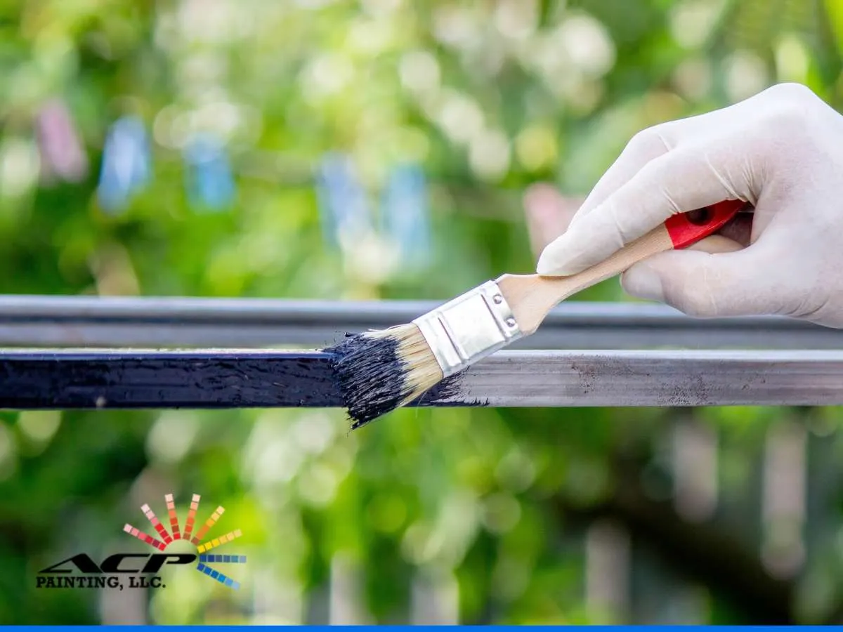 A hand wearing a white glove applies black paint to a metal bar with a brush, showcasing the services of Maricopa painting contractors specializing in metal protection.