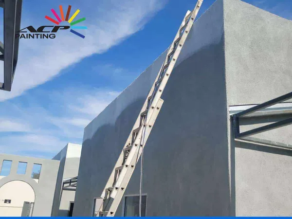 Freshly painted grey masonry block wall on an Arizona building with a ladder leaning against it